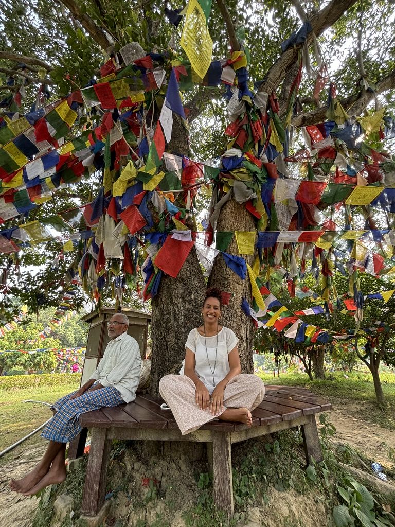 Cat Peterson sitting beneath a tree hung with prayer flags